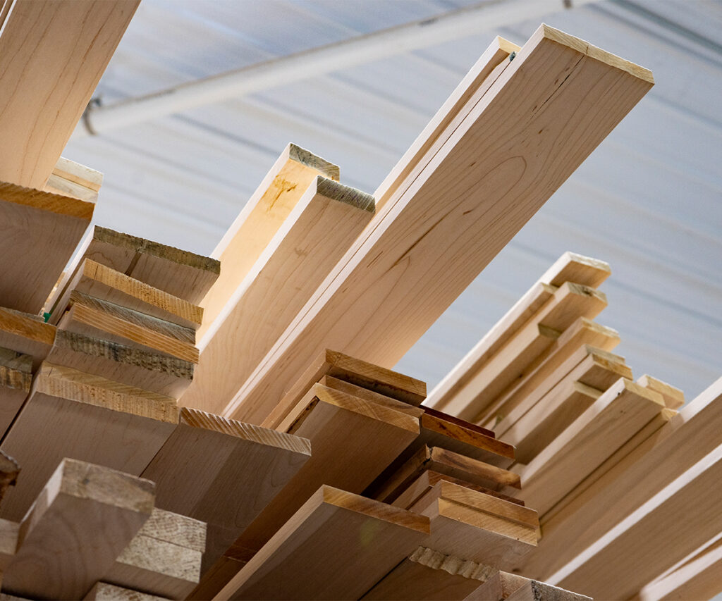 Stack of kiln-dried hardwood boards used for sustainable Amish furniture in a small shop.