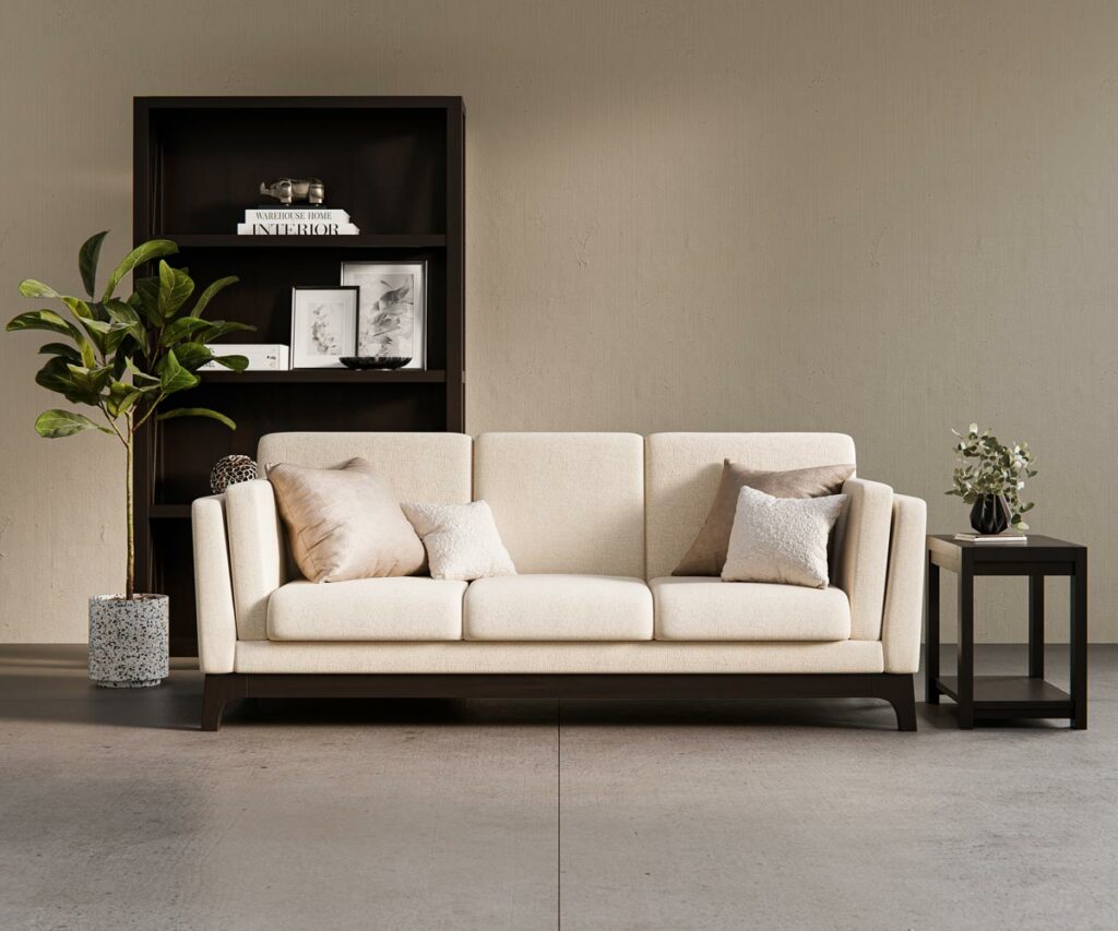 A contemporary living room featuring a cream upholstered sofa with dark wood accents, a matching side table with greenery, and a black open-shelf bookcase, showcasing Amish furniture styles.