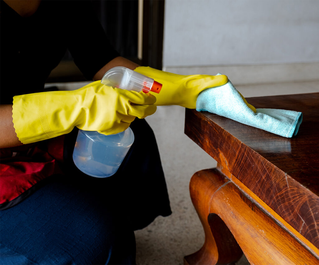 Cleaning solid wood table with microfiber cloth and spray bottle