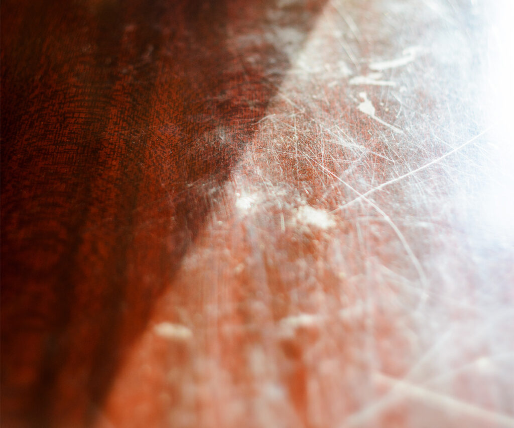 Scratched solid wood tabletop surface showing finish damage